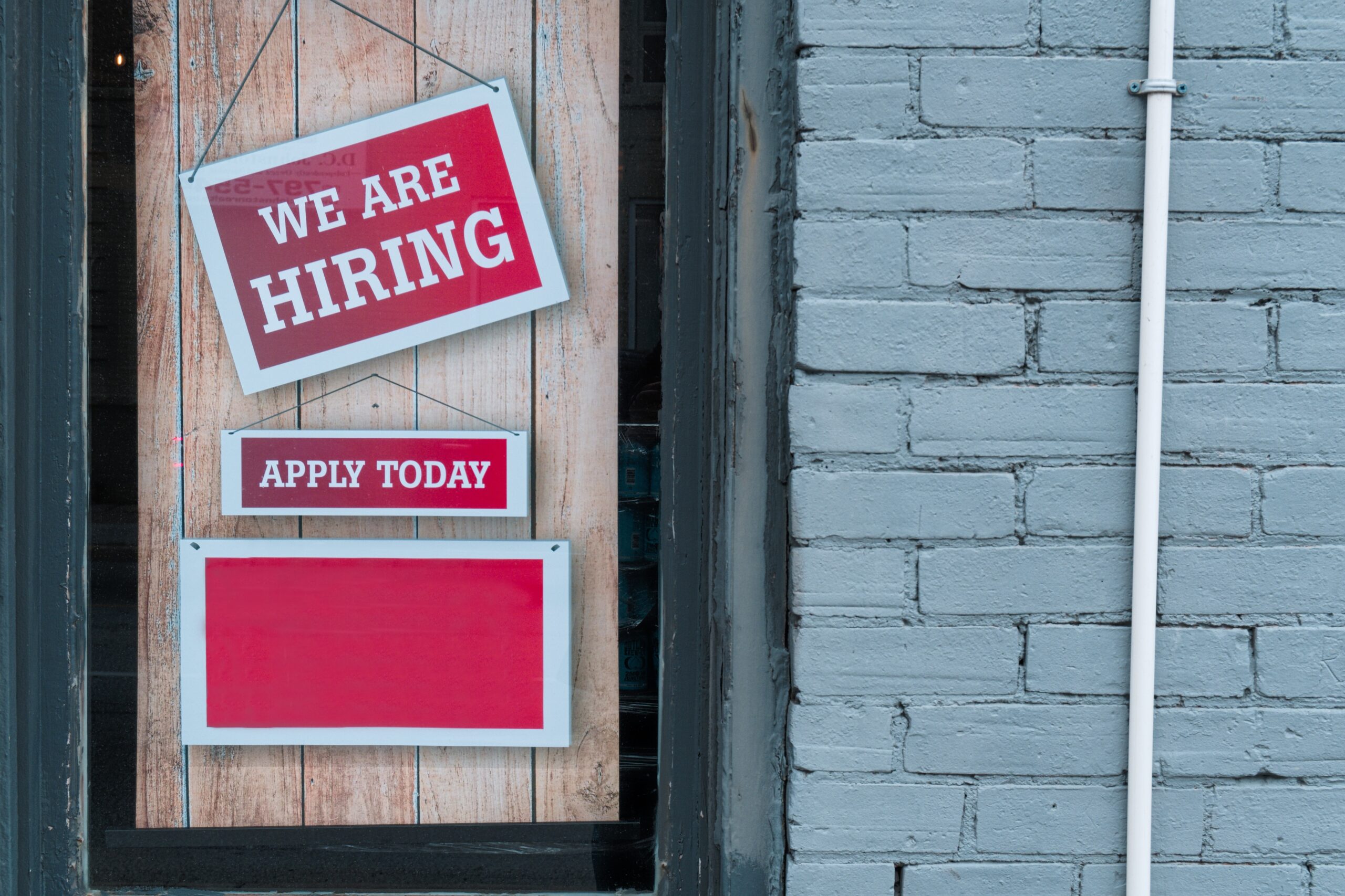 image showing WE ARE HIRING signs hanging on a door to support article content on job application automation for a school website